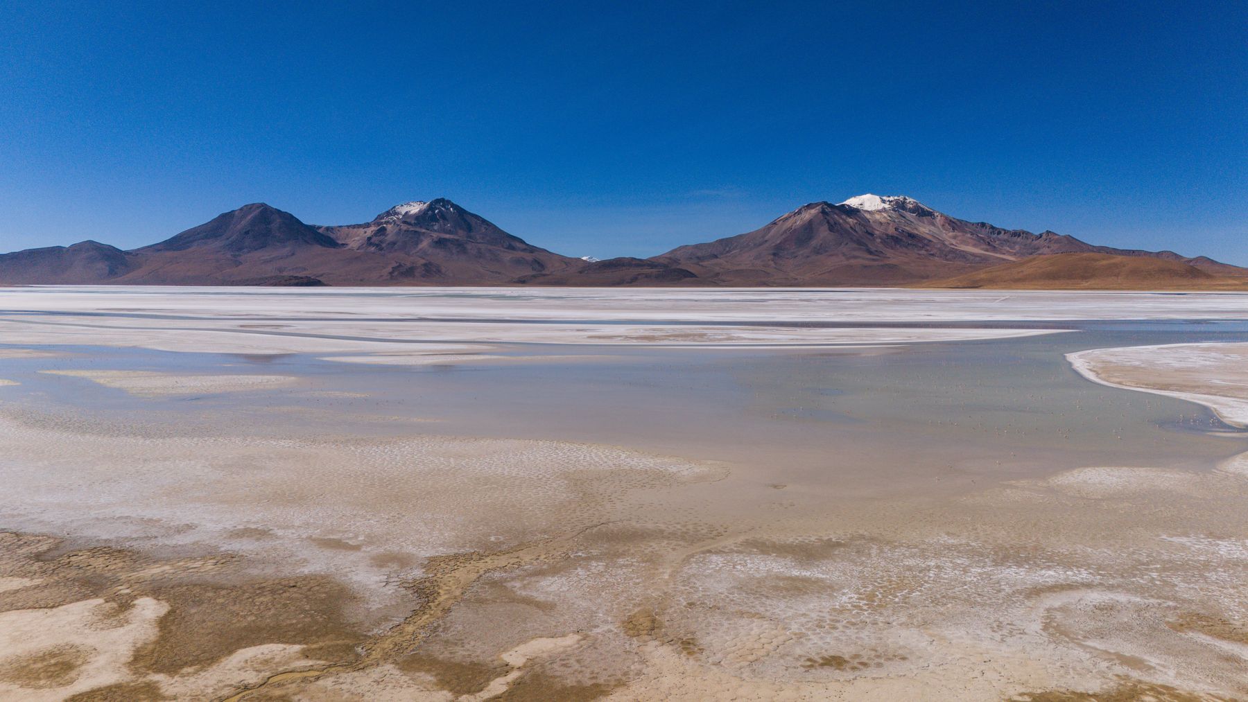 Vista aérea del Salar de Surire con volcanes al fondo